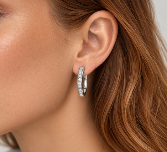 A close-up of a woman's ear wearing a hoop earring set with diamonds