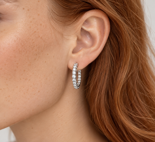 A close-up of a model's ear wearing a small white gold hoop earring set with diamonds