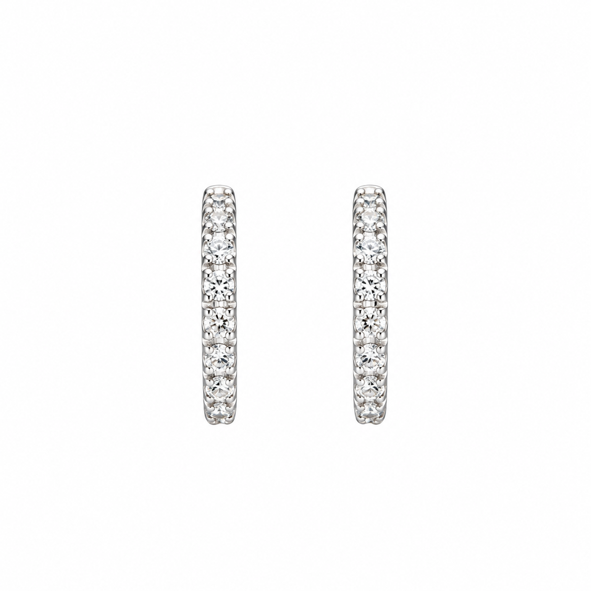 A pair of silver-toned huggie hoop earrings paved with round clear stones, shown against a plain white background.